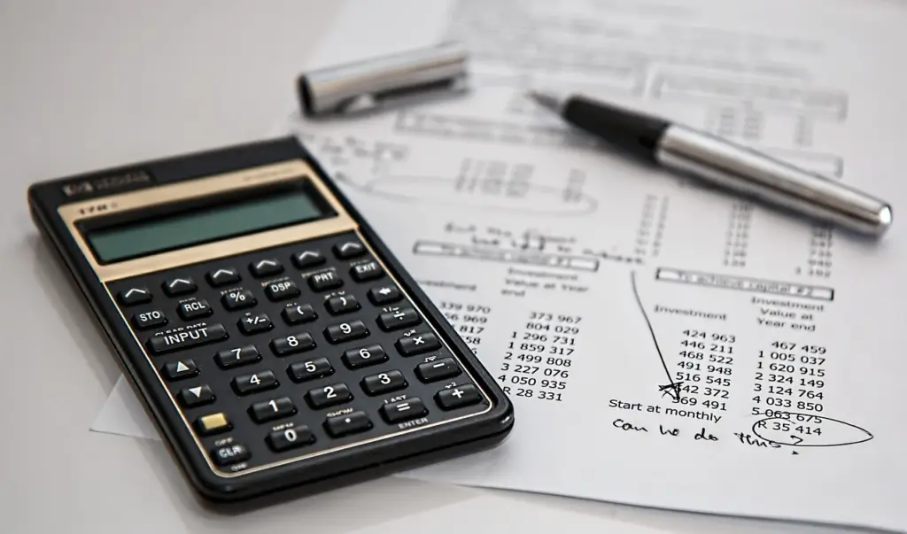 calculating mortgage costs on a calculator with documents