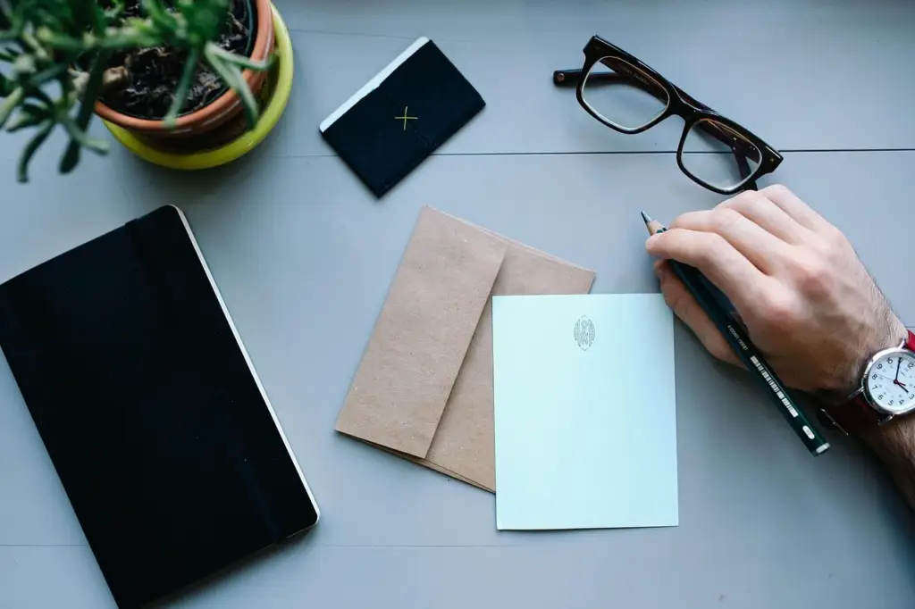 Close-up of a person writing a budget on a spreadsheet with coins and a credit card nearby